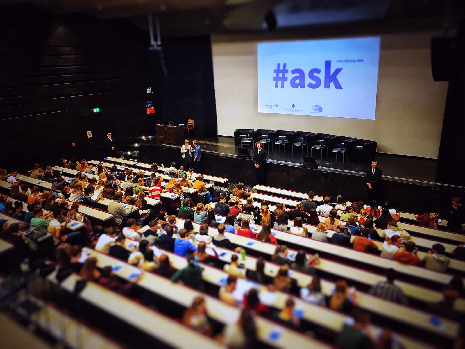 Publikum in einem Hörsaal mit Präsentation auf der Leinwand.